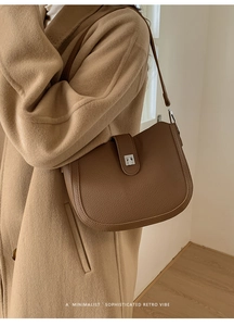 Close-up of brown litchi pattern leather bucket bag worn with a wool coat in retro style