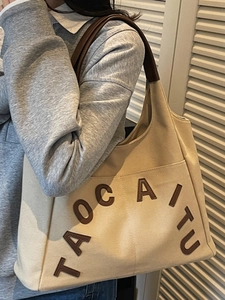 Retro canvas tote bag with brown TAOCAITU letter patch and leather handles in minimalist style
