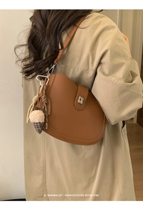 Caramel lychee leather saddle bag shown on beige trench coat with ice cream charm