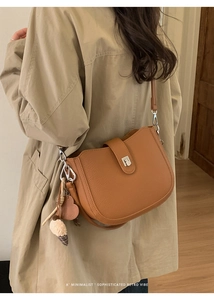 Close-up of retro brown saddle bag with heart charm and silver metal clasp