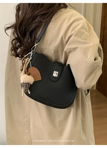 Detail of black lychee leather bucket bag with silver twist lock and acorn charm pendant