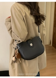 Retro black leather saddle bag shown on model wearing a beige trench coat