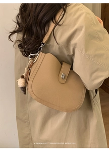 Close-up of retro brown pebbled leather bucket bag with silver buckle and plush charm