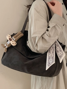 Large brown shoulder tote bag with floral scarf and bunny pendant on casual beige outfit