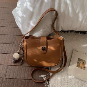 Detail of vintage brown pebble leather crossbody bag with silver buckle and charm