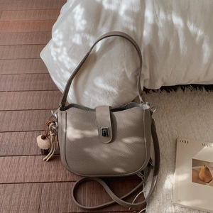 Detail of lychee pattern leather bucket bag with metal lock and cute plush charm