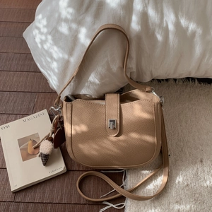Close-up of brown lychee grain leather bucket bag with metal buckle and cute ice cream charm