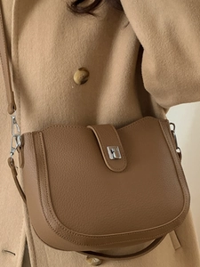 Chic tan saddle bag in lychee pattern leather with silver clasp on wool coat