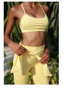 Detail of high-waisted pale yellow yoga set featuring decorative waist ties in outdoor setting