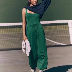 Close-up of dark green yoga bodysuit and matching drawstring joggers in a tennis court setting