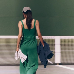 Back view of a woman wearing a dark green athletic tank top and wide-leg yoga pants