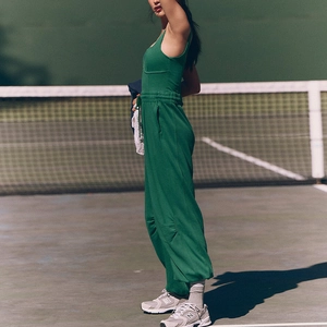Detail of dark green athletic set with drawstring waist and strappy top on a tennis court