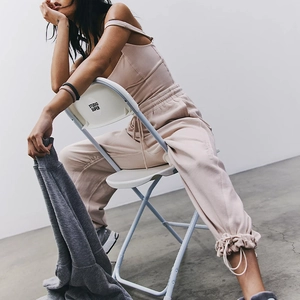 Detail of light apricot yoga jumpsuit with drawstring cuffs and slim straps