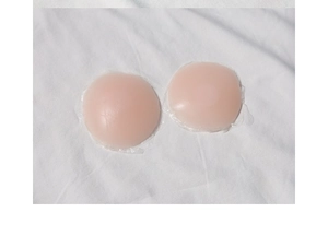 Close-up of thin nude round silicone pasties on white fabric showing soft texture