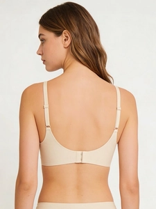 Detail view of the back of a seamless beige wireless bra with adjustable straps for women