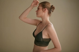 Detail of dark green lace bralette with triangle cups and delicate floral patterns