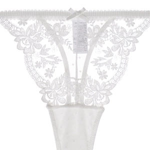 Détail du string en dentelle blanche avec texture florale et petit nœud satiné