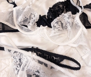 Exquisite floral lace lingerie set with silk bows on textured white satin backdrop