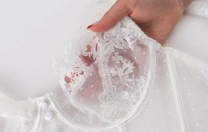 Détail d'un corset en dentelle blanche avec broderie florale et texture en tulle à pois