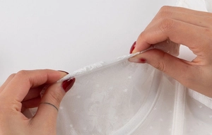 Détail du tissu en dentelle blanche montrant l'élasticité et la texture délicate à pois