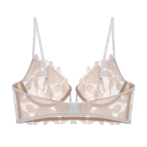 Close-up of fine floral embroidery and sheer mesh detail on beige lace bralette