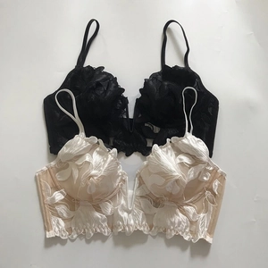 Detailed close-up of floral embroidery on thin V-neck lace bralettes in black and cream
