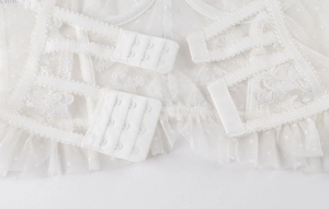 Détail de la fermeture dorsale d'un soutien-gorge en dentelle blanche à trois rangées