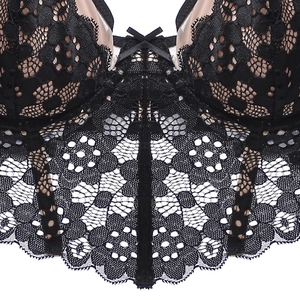 Détail en gros plan du corset en dentelle florale noire avec doublure chair et nœud