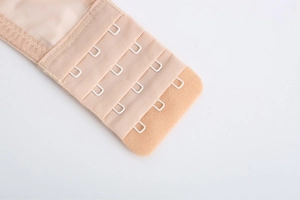 Detailed macro view of beige bra back closure with 4 rows of 3 hooks and soft mesh
