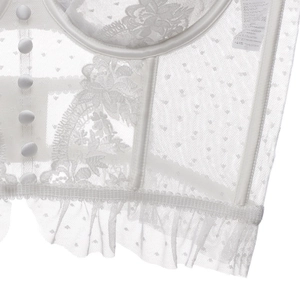 Détail d'un corset blanc avec broderie florale, tulle à pois et boutons en tissu