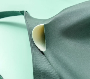 Macro view of seamless mesh V-neck bra showing detachable beige padding in dark green fabric
