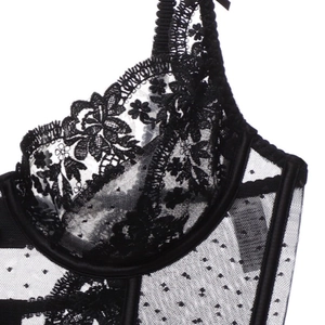 Détail rapproché de dentelle florale noire et résille à pois sur corset à armatures