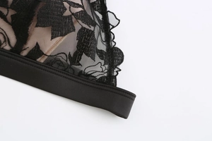 Detail of floral rose embroidery on black lace bralette with smooth elastic band