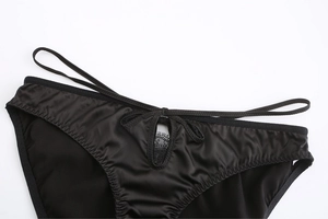 Dettaglio di lingerie in raso nero con apertura a goccia e finiture in pizzo eleganti