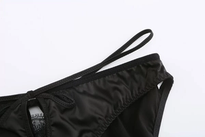 Dettaglio di lingerie in raso nero con pizzo ciglia e spalline incrociate eleganti