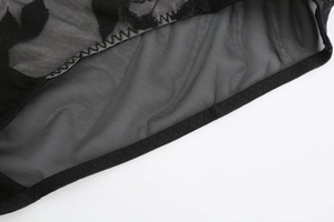 Detailed macro view of black sheer mesh fabric with rose embroidery and fine stitching