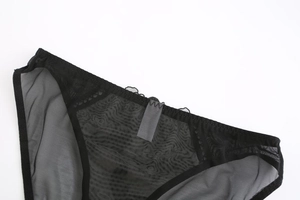 Detail of black semi-transparent mesh fabric with a minimalist stitched waist label