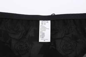 Detail view of black lace bralette tag showing fabric material and size M information