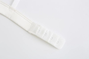Close-up detail of white bralette back with four-row hook-and-eye closure and fine mesh texture