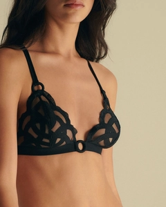 Detailed close-up of black lace triangle bralette with geometric mesh and ring accents