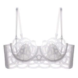 Detail of white lace balcony bra with intricate spiral embroidery and sheer mesh fabric