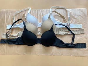 Flat lay of seamless gather bras in black, beige, and white with adjustable straps