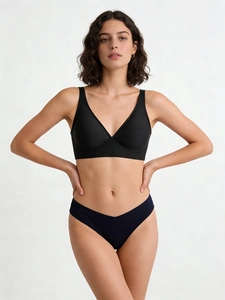 Detail view of seamless V-neck bralette and low-rise panty set on model for sports comfort