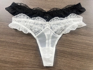 Detail of lace floral embroidery and sheer mesh on black and white thong set