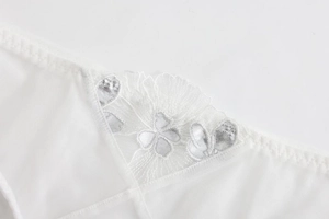 Close-up of white lace mesh fabric with exquisite silver floral embroidery detail