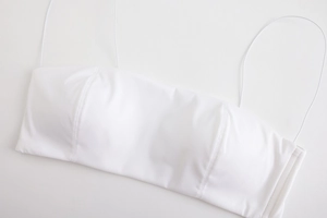 Detailed top-down view of white seamless thin-strap bralette with minimalist flat texture