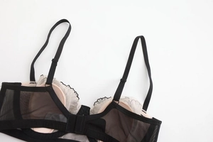 Detailed view of French lace embroidery and sheer mesh on this elegant black bra