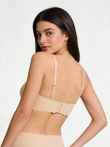 Close-up of seamless beige bra with wavy edges and three-row back clasp on model