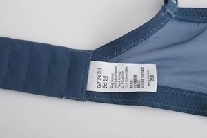 Detail shot of navy blue lace bra showing the mesh side wings and laundry care labels