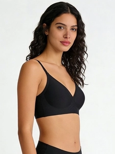 Detail of a seamless black bra with thin straps and smooth texture on a female model